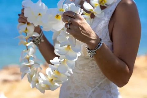 A white plumeria lei in her hands