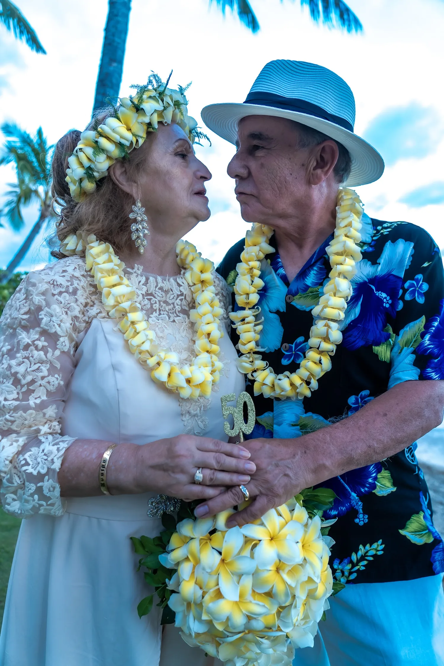 Holding the golden 50 with their rings and leis