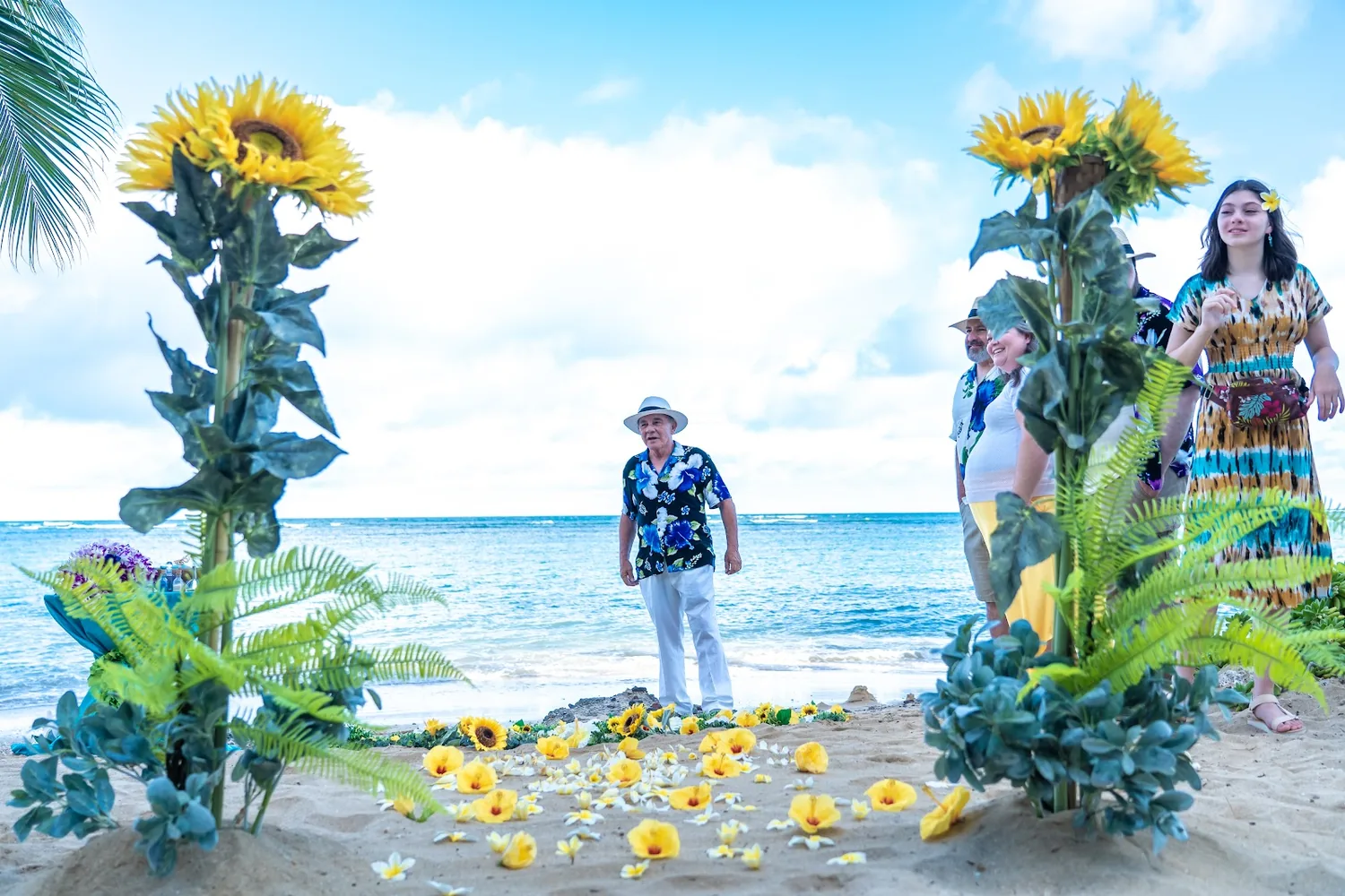 Sunflower stands framing the beach ceremony spot as guests arrive