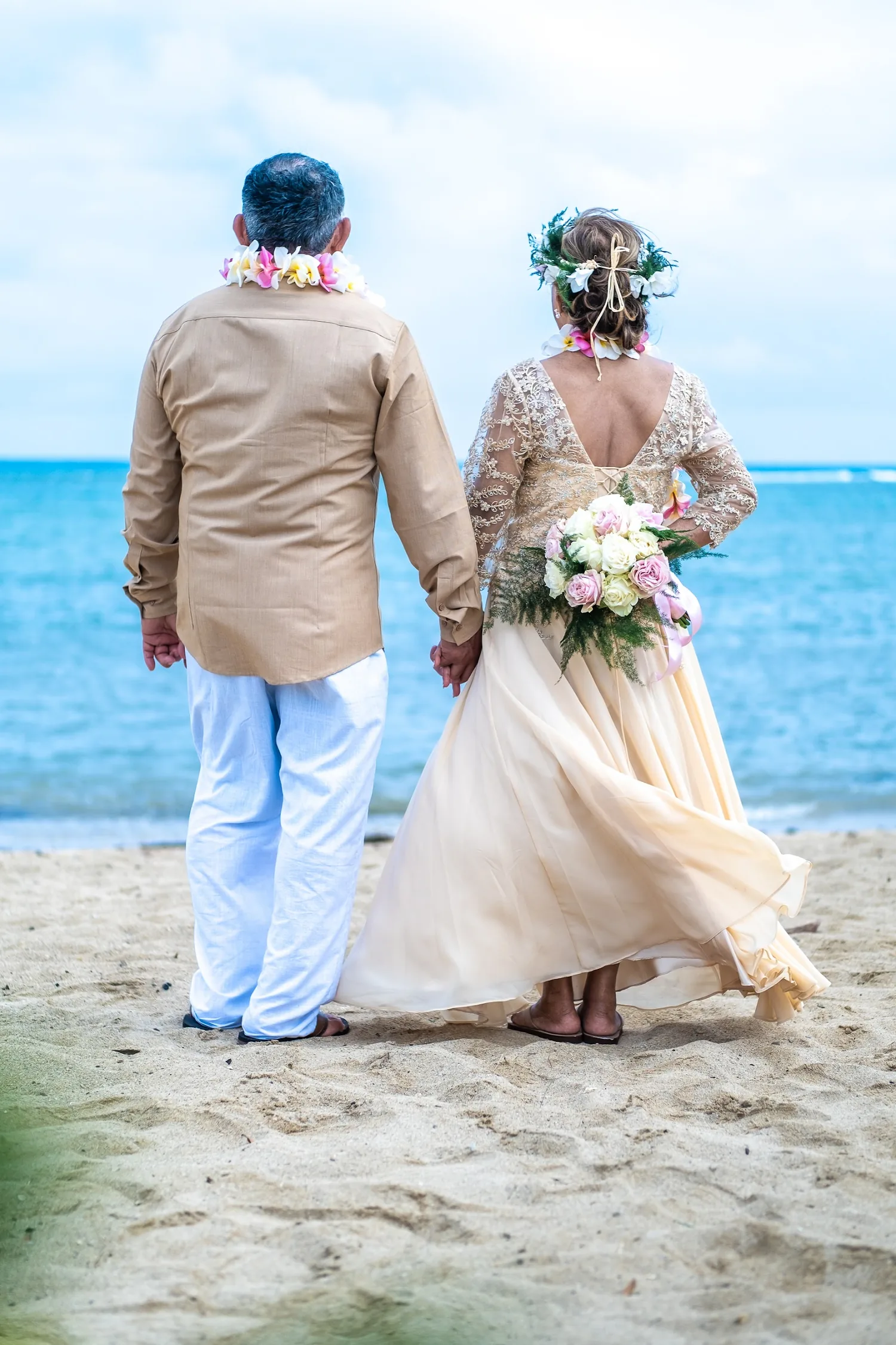 Her gown blowing in the ocean breeze as they hold hands