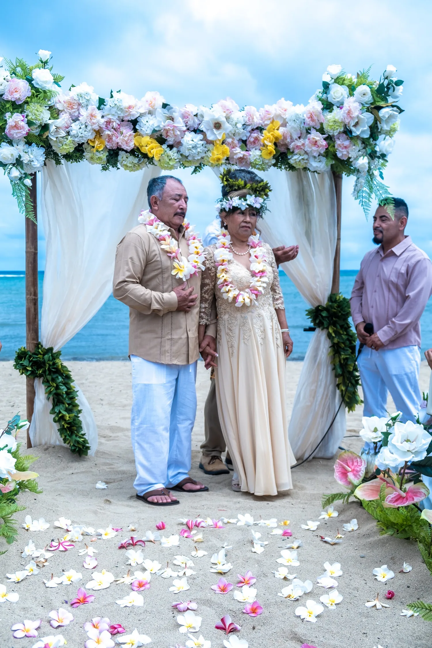 Holding hands under the arch with the officiant beside them