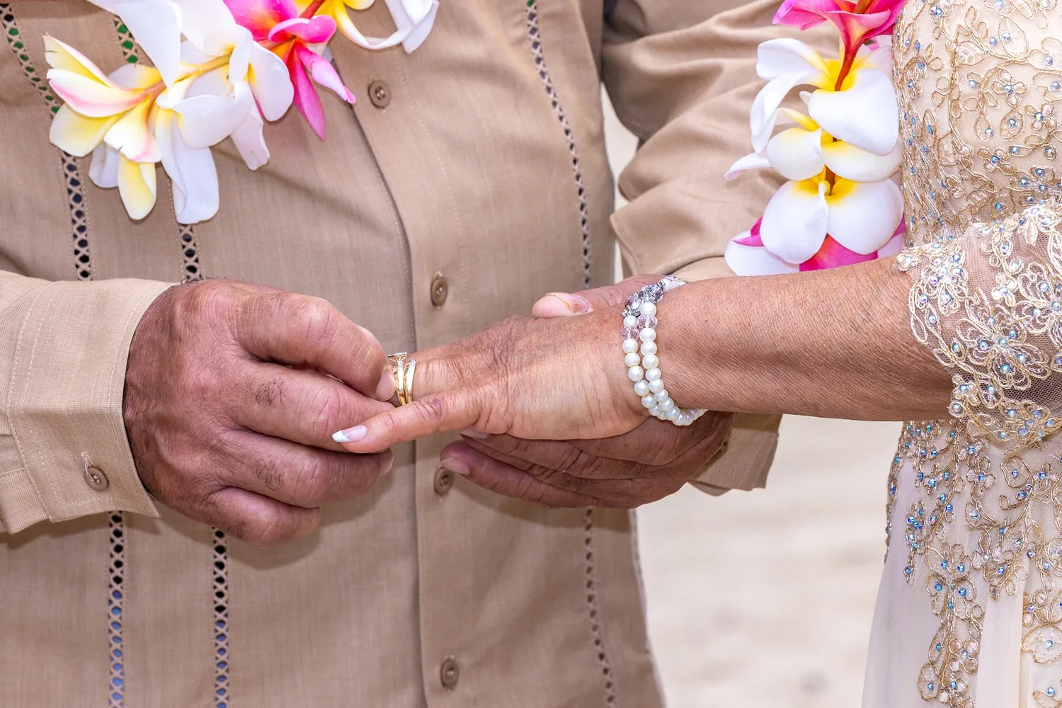 Close up of the husband placing the ring on his wife's finger