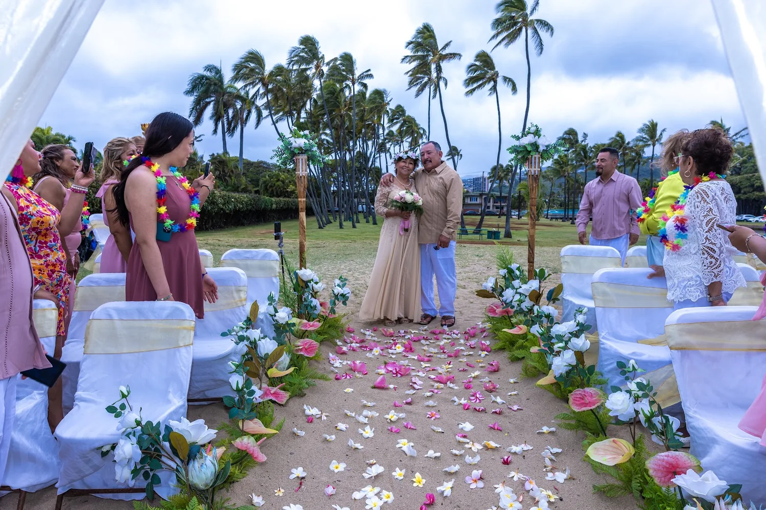 Walking down the aisle together with palm trees and guests on both sides