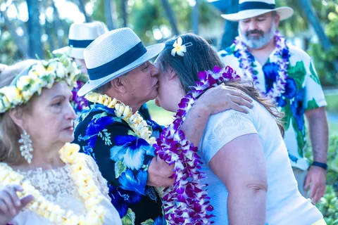 A family hug in purple and yellow leis