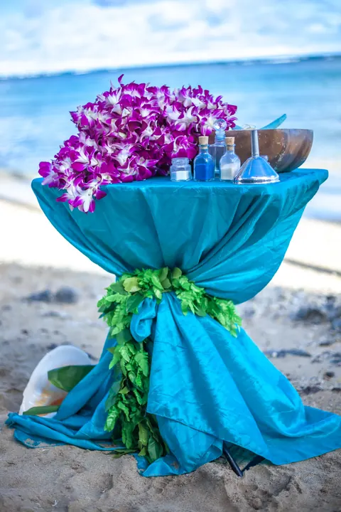 A turquoise wrapped pedestal with purple orchids on the beach