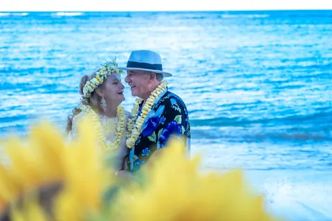 Sunflowers in front as the couple stands by the sea