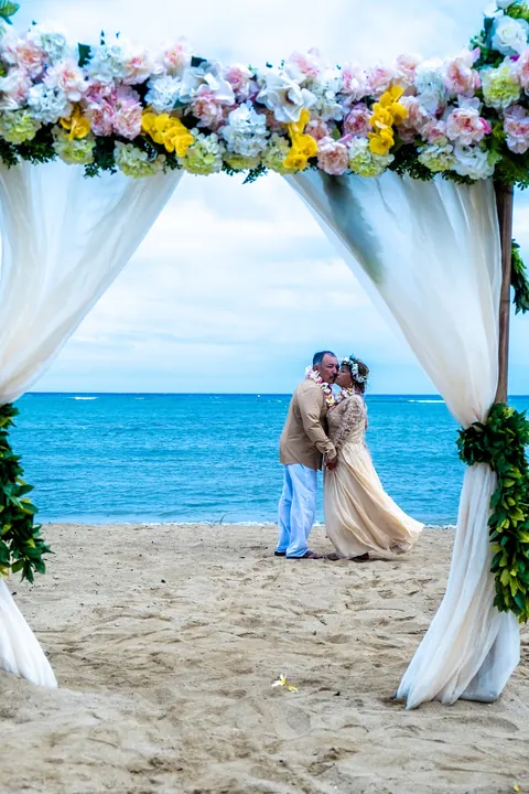 The couple framed by white curtains with the ocean behind