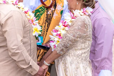The couple holding their wedding rings