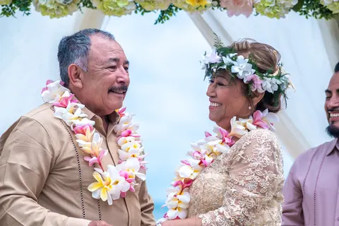 Smiling at each other in their plumeria leis