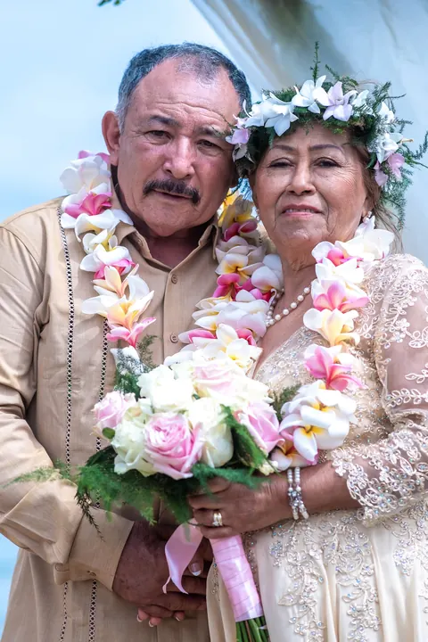 Smiling together in pink plumeria leis