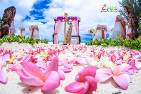 Carved tiki men and pink plumerias frame the pink draped archway at Waimanalo
