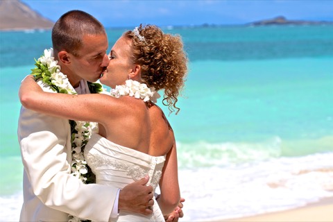 Karissa kisses her new husband on the sand by the ocean