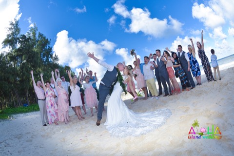 Kenny dips Kate as their guests cheer on the beach