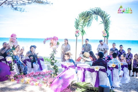 Family and friends gather for the vow renewal under the palm arch