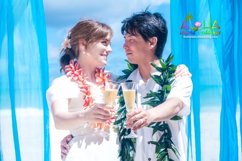 Toshi and Suzanne toast with guava juice under their beach arch
