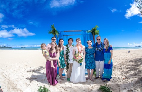 Toshi and Suzanne with their family under the blue archway on the beach