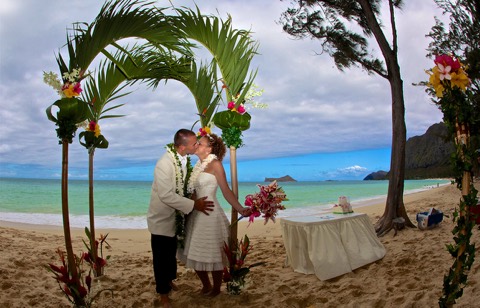 Another kiss under the palm arch with the ocean behind them