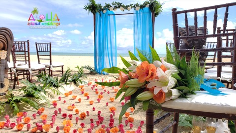 The bride's tropical bouquet resting on a chair beside the petal aisle and blue archway