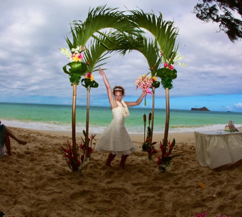 Karissa celebrating under the green palm arch at Waimanalo