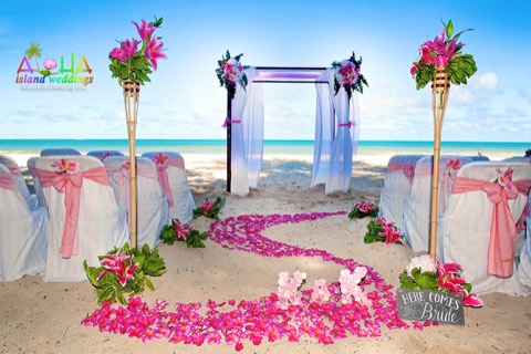 Swirls of pink plumerias, rose gold chairs and tiki torches wrapped in greenery at Waimanalo