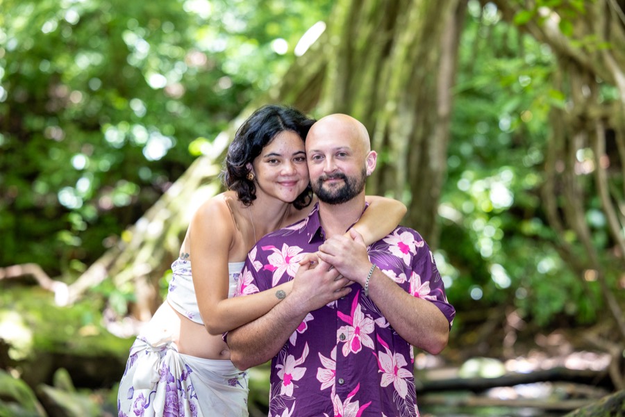 Smiling couple embracing in front of a giant banyan tree in the rainforest