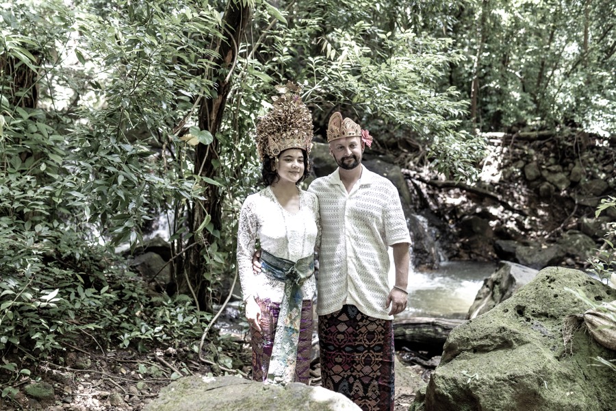 Couple in golden headdresses beside a rainforest stream on Oahu