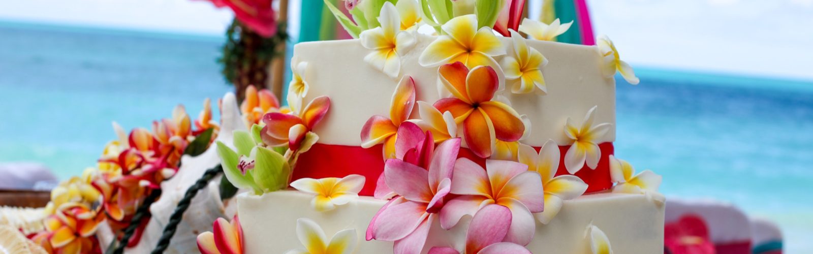 Wedding cake decorated with plumeria flowers on the beach